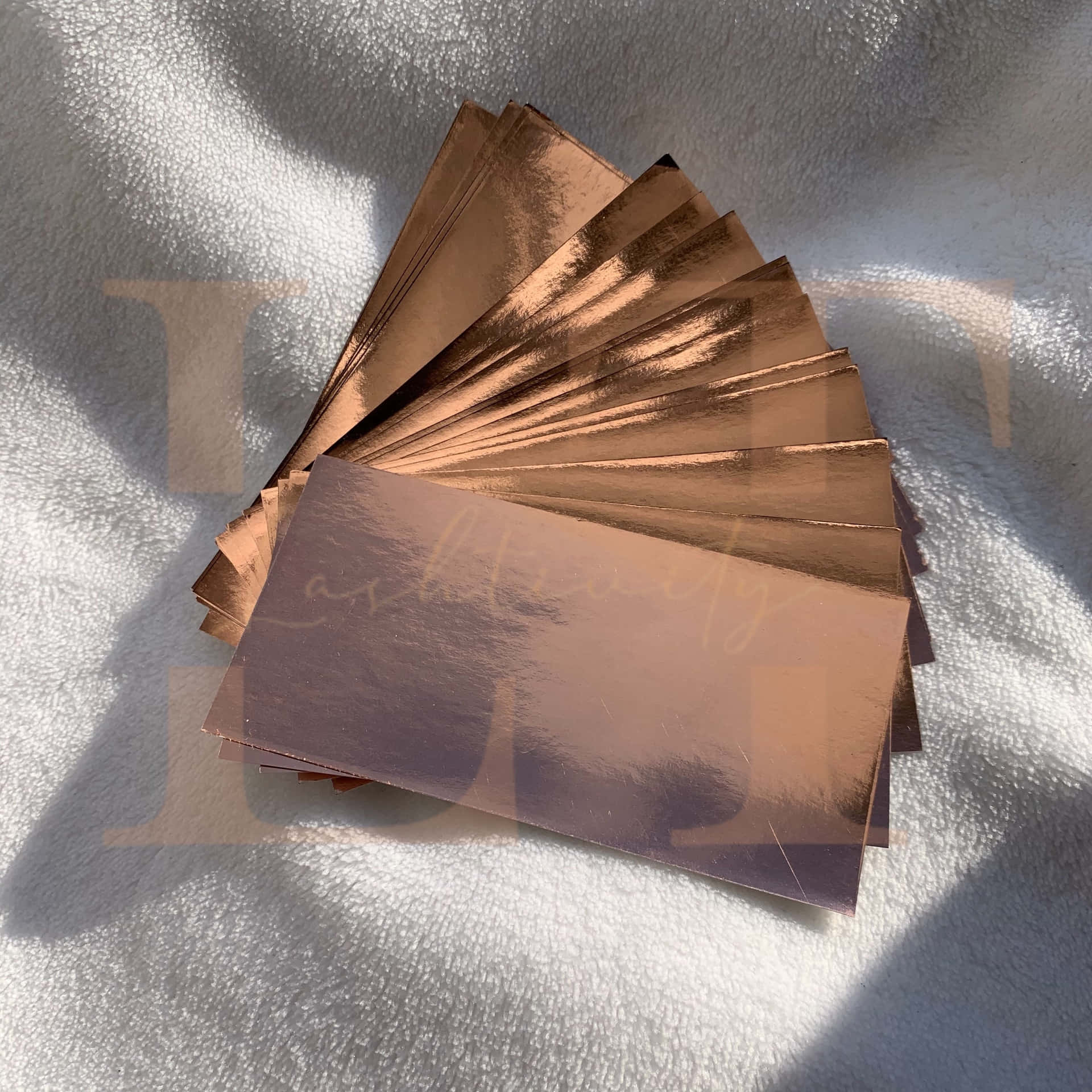 A Set Of Copper Foil Cards On A White Blanket Background