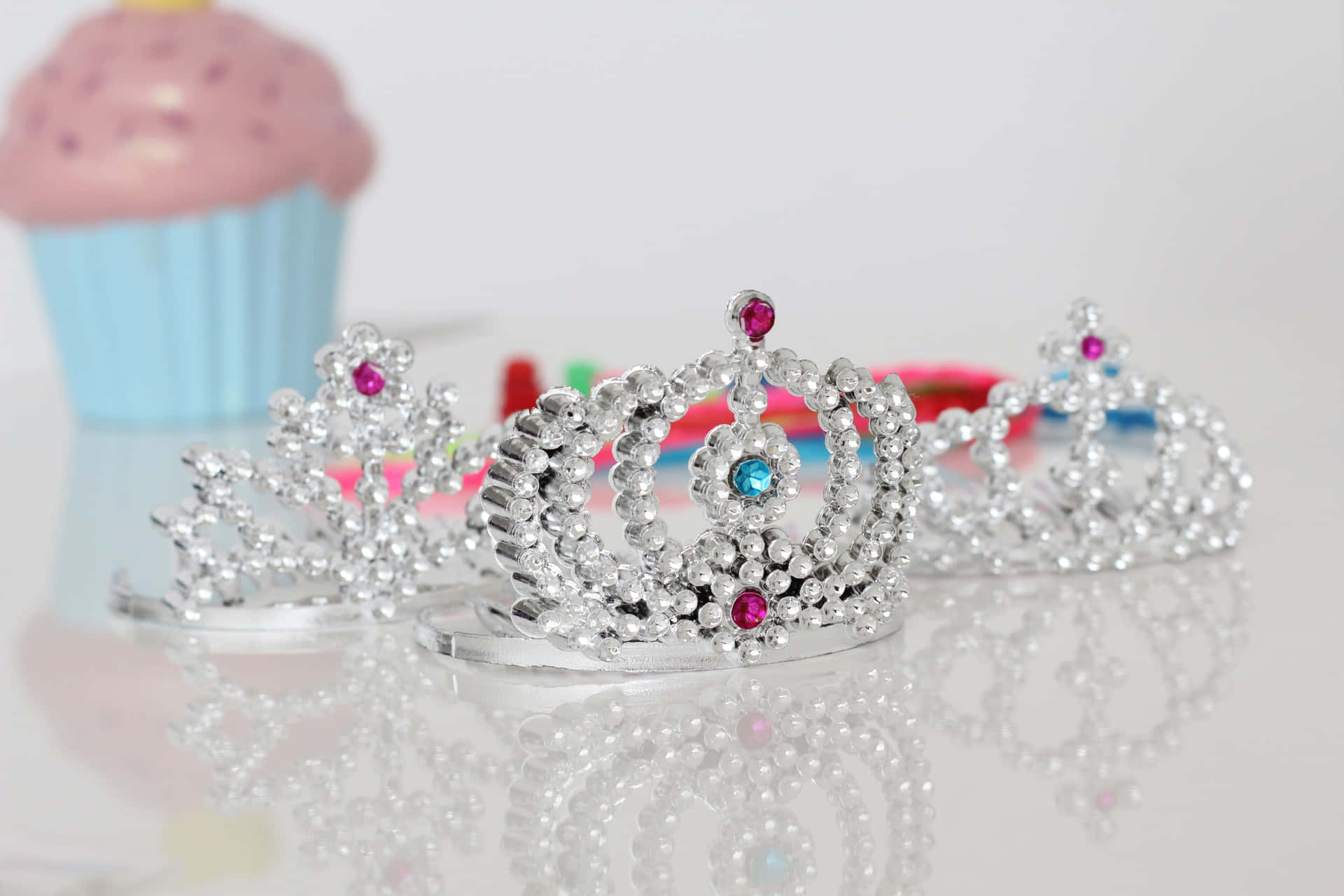 A Set Of Tiaras And Cupcakes On A Table Background