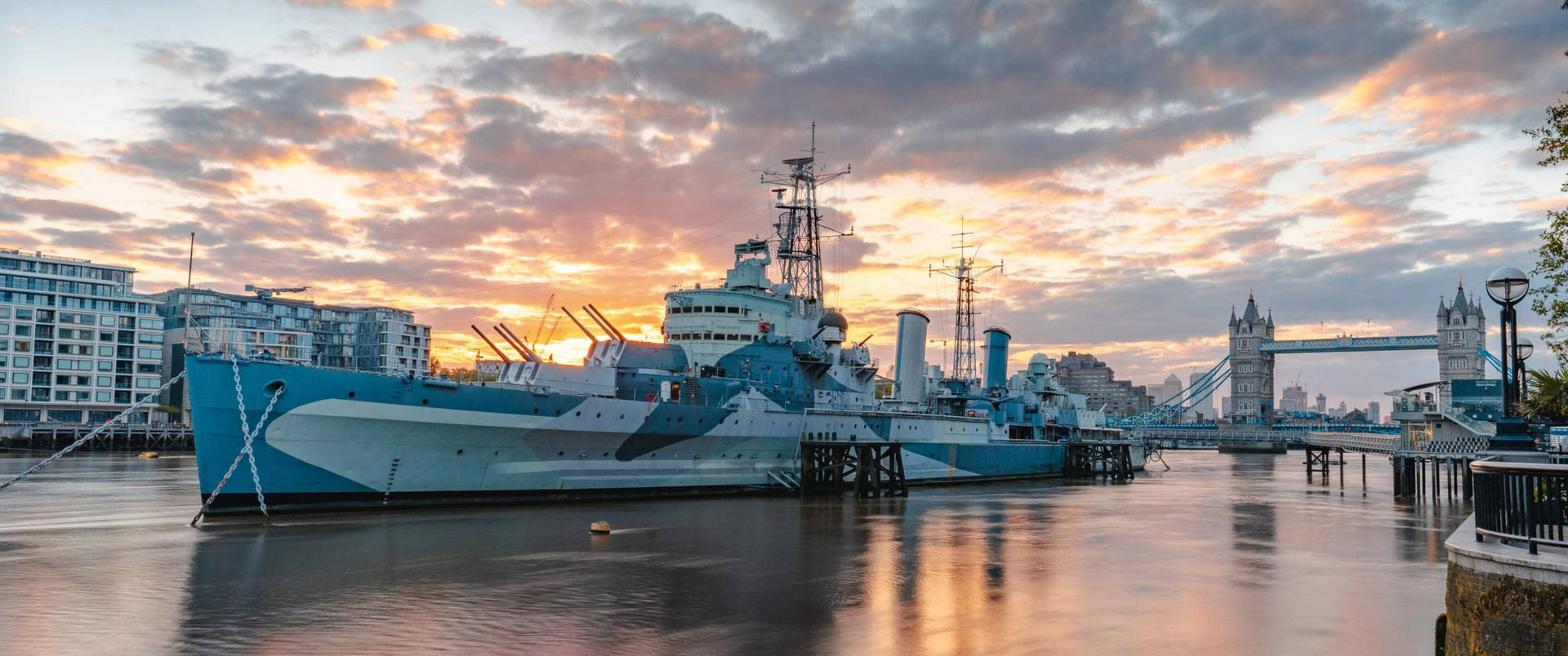 A Ship Docked In The River Near A City Background