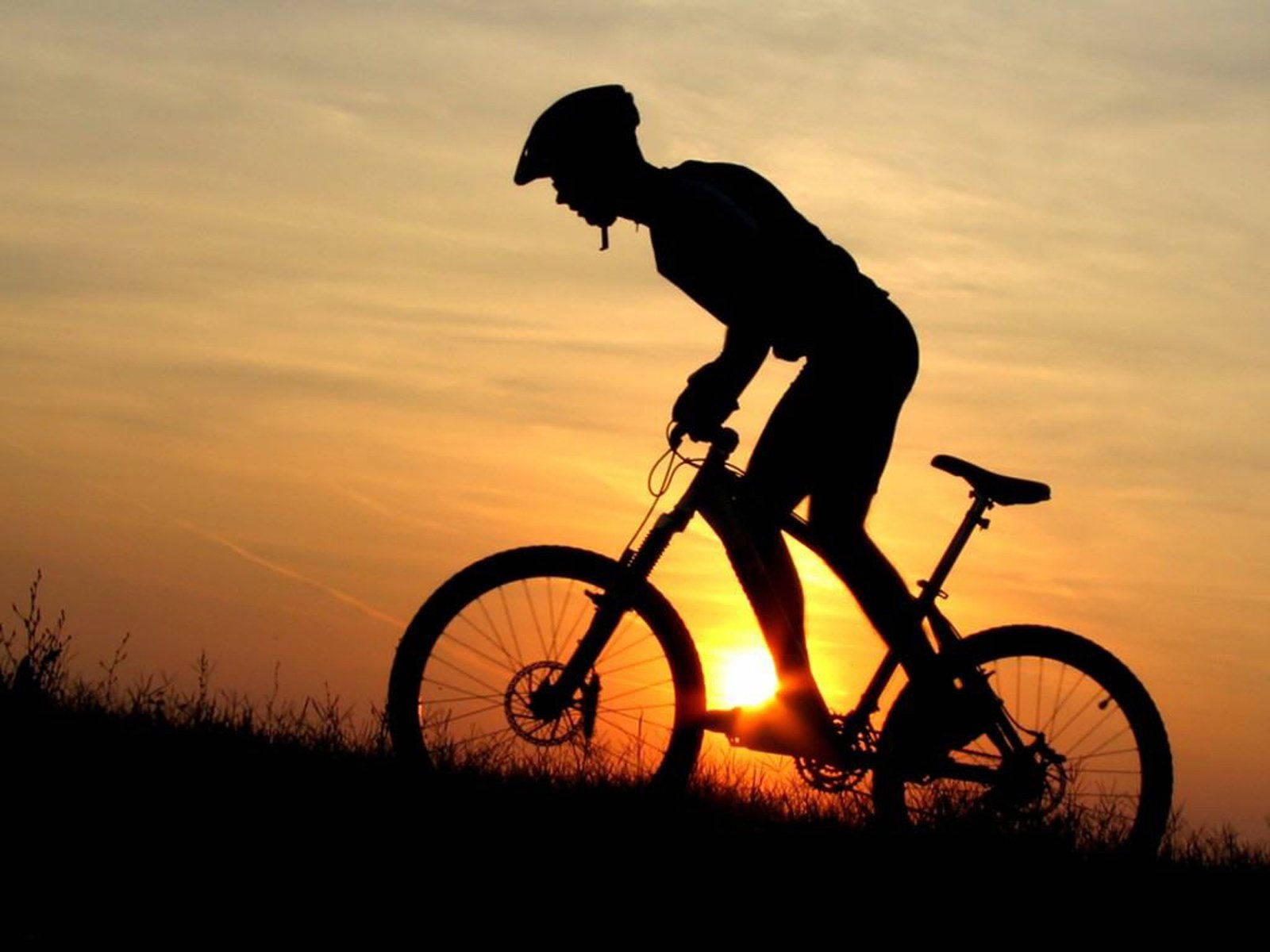 A Silhouette Of A Cyclist Enjoying A Beautiful Sunset Bike Ride. Background