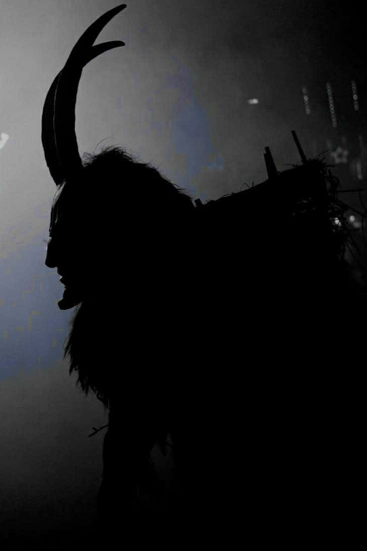 A Silhouette Of A Demon With Horns On His Head Background