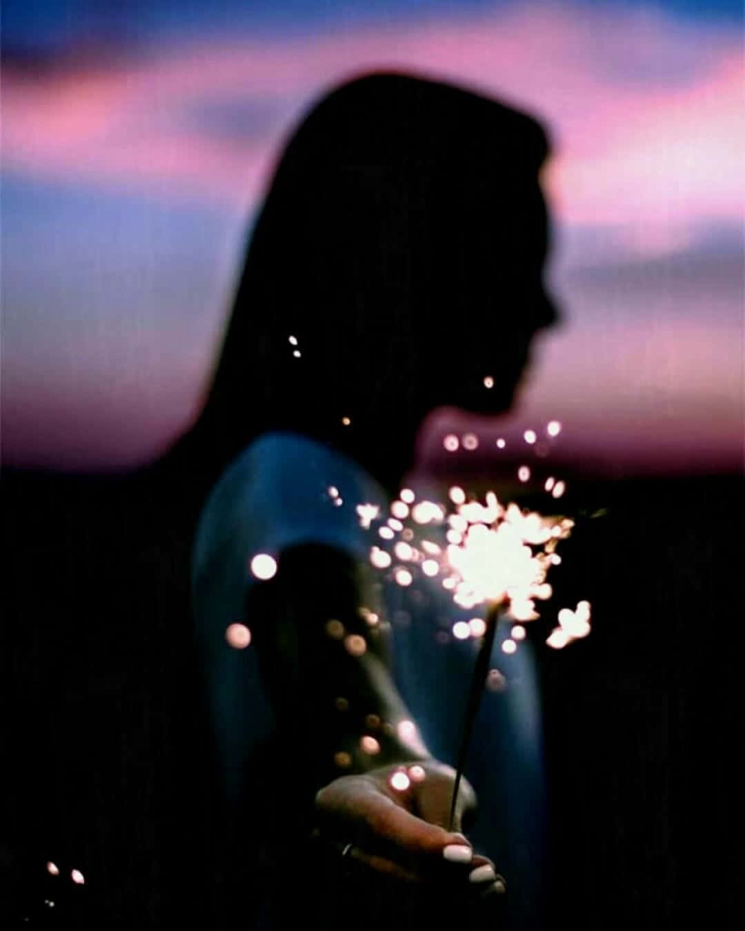 A Silhouette Of A Woman Holding A Sparkler Background