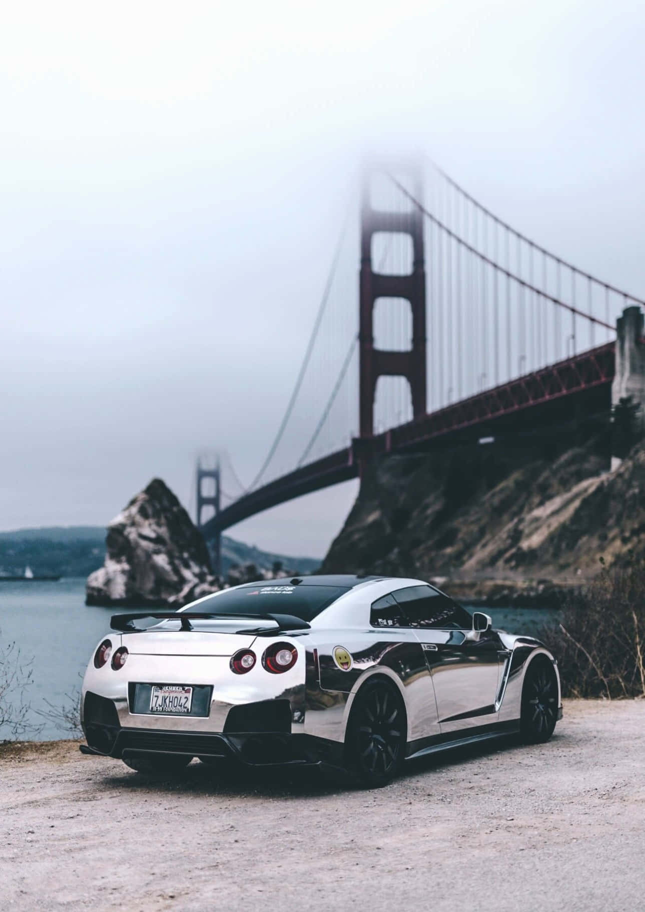 A Silver Car Is Parked In Front Of The Golden Gate Bridge Background