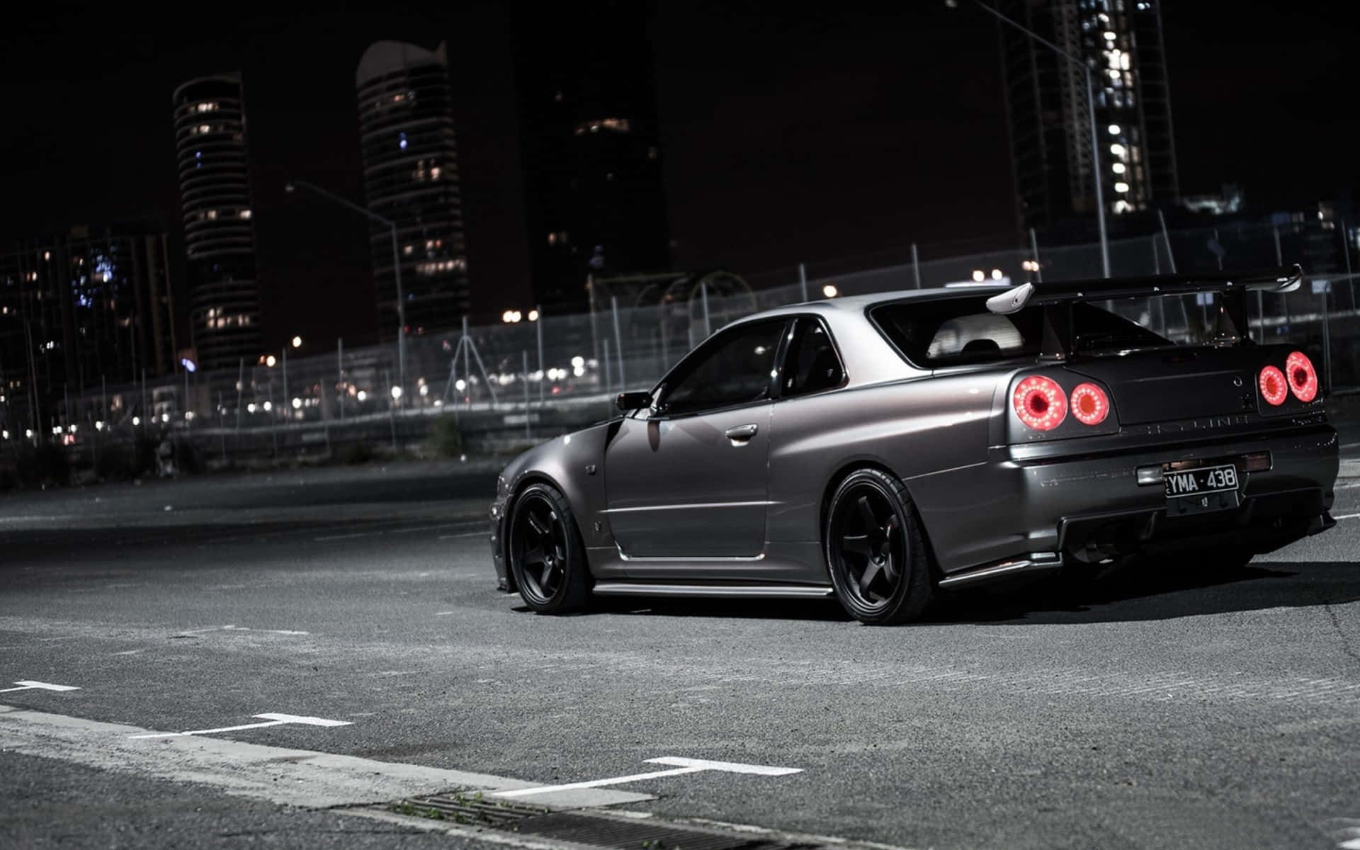 A Silver Car Is Parked On A Street At Night Background