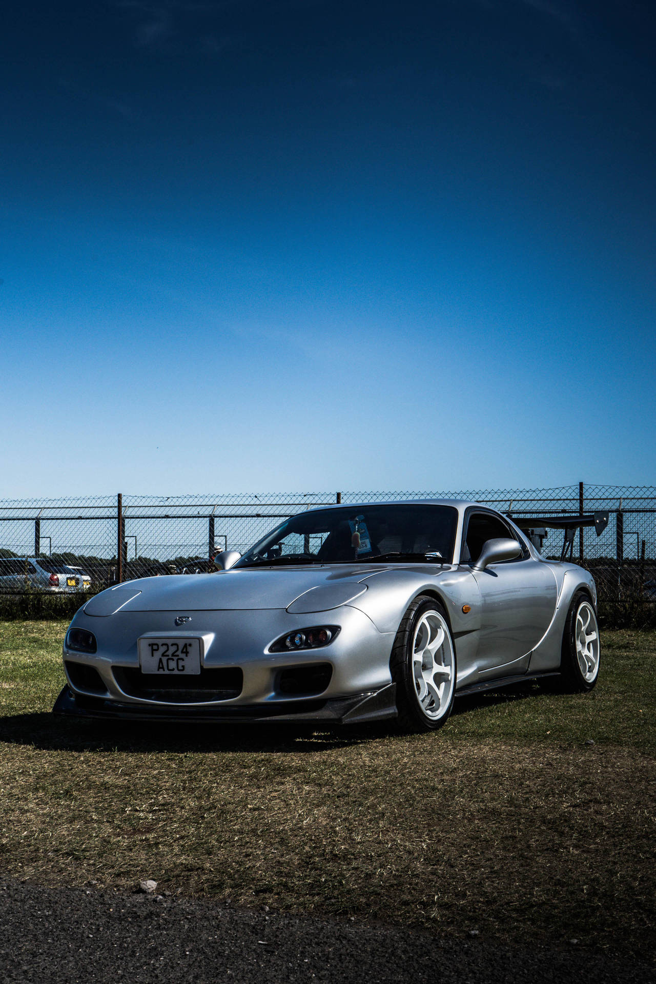 A Silver Car Parked On A Grassy Field Background