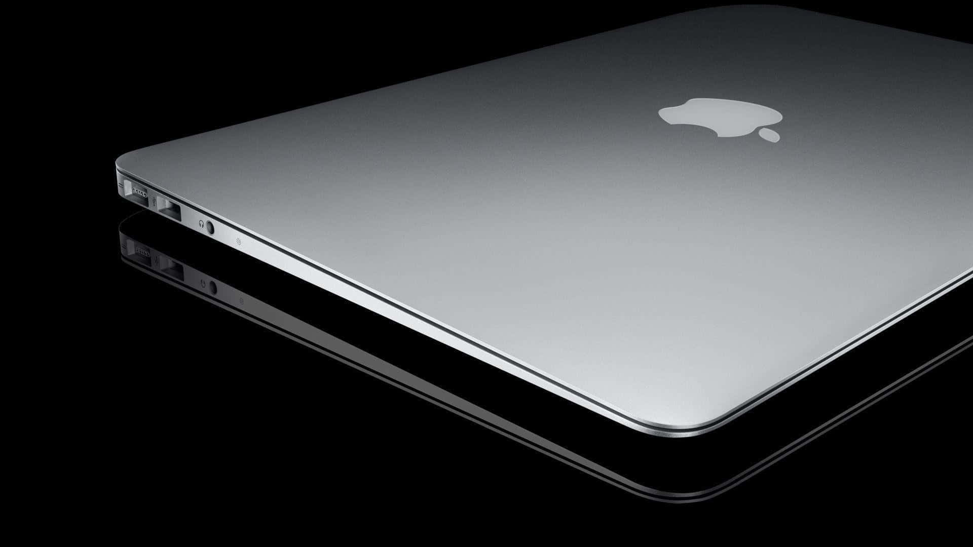 A Silver Macbook Pro Is Shown On A Black Surface