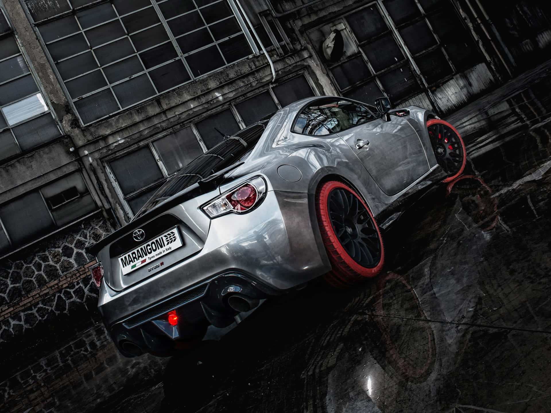 A Silver Sports Car Is Parked In A Rainy Street Background