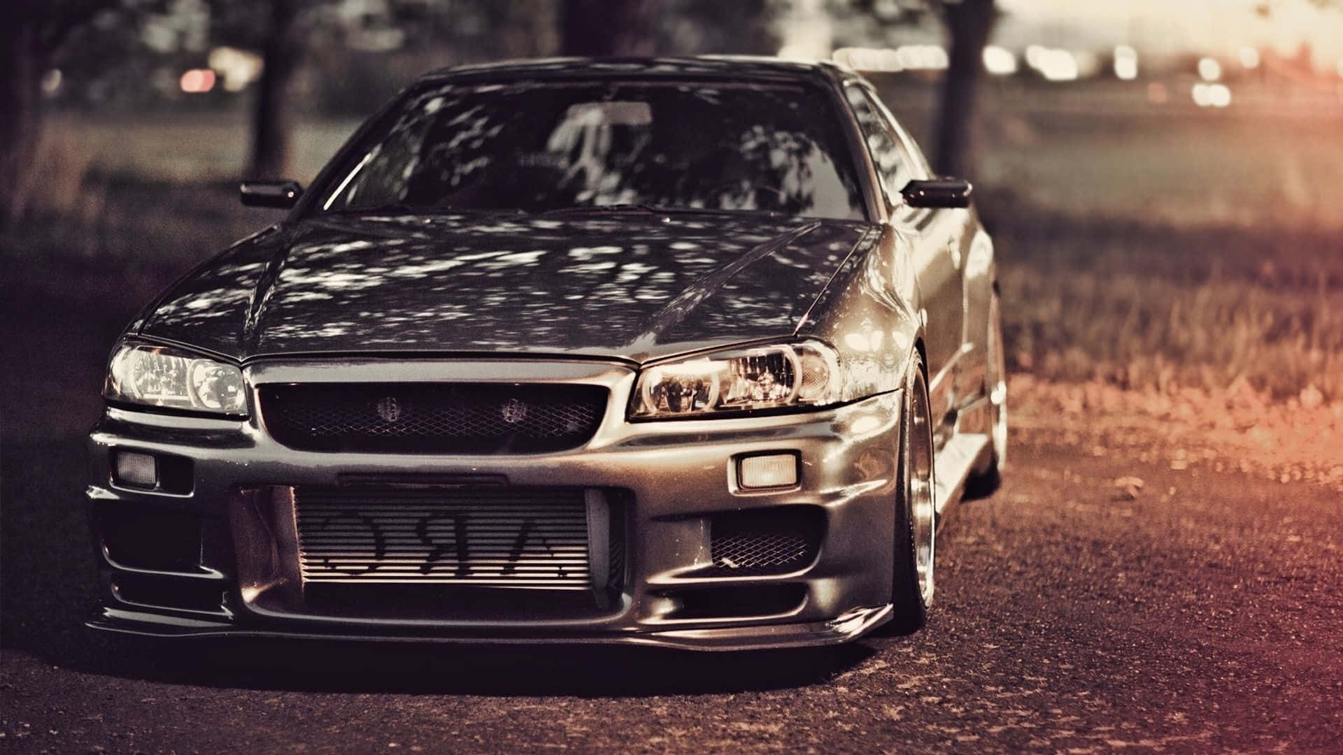 A Sleek Silver Nissan Skyline Sports Car In A Stunning Sunset Background