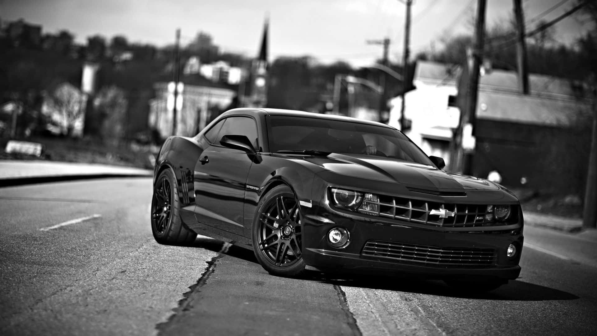 A Sleek Sports Car Zooming Through A Deserted Highway Background