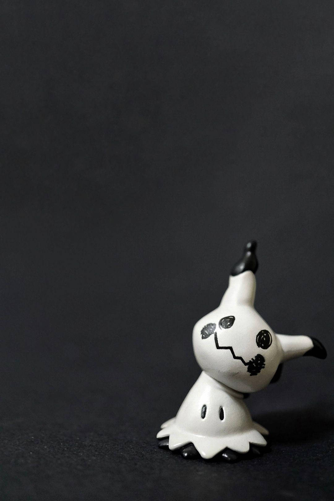 A Small Figurine Of A Ghost Sitting On A Black Surface