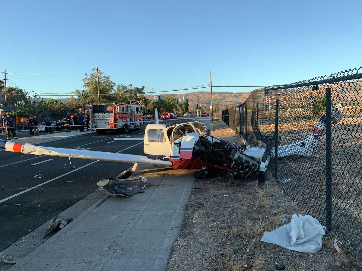 A Small Plane Crashed Into A Fence Near A Road Background