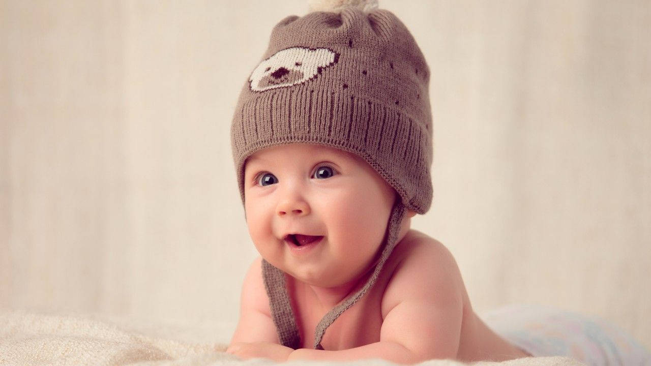 A Smiling Baby In A Brown Bonnet