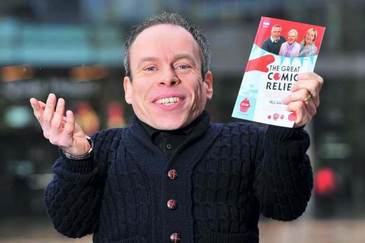 A Smiling Warwick Davis Posing For A Portrait Background