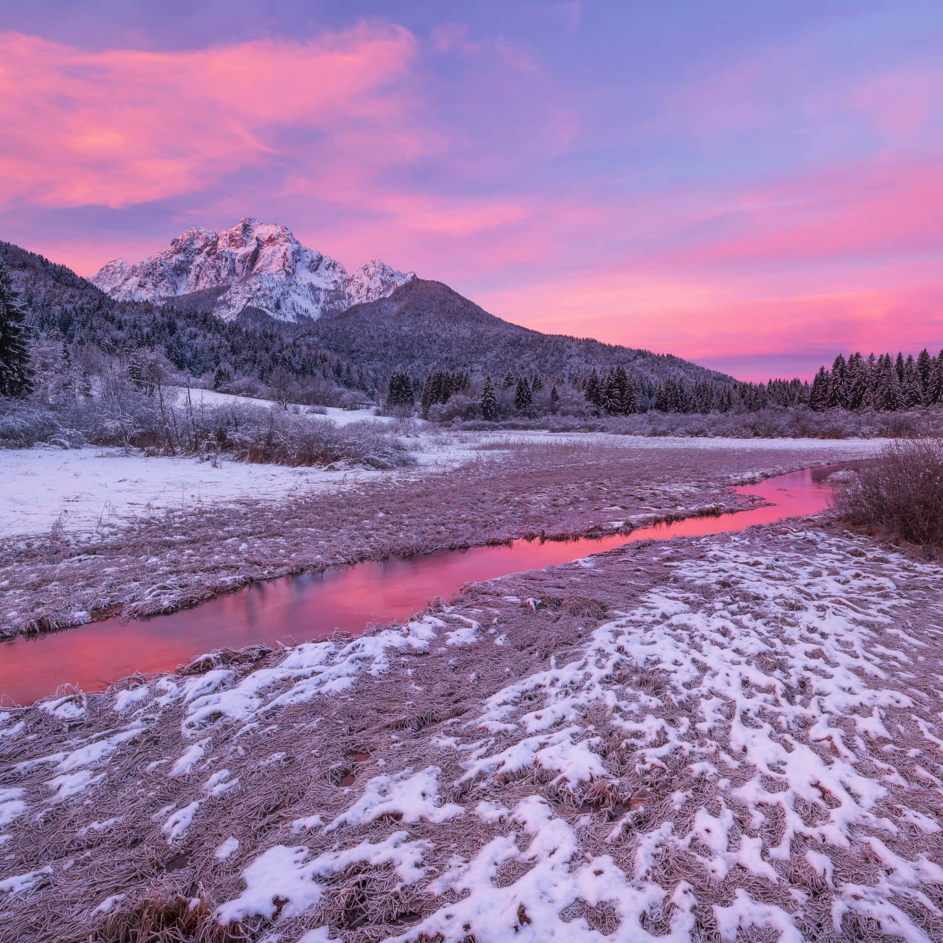 A Snowy Mountain With A Pink Sky And A River Background