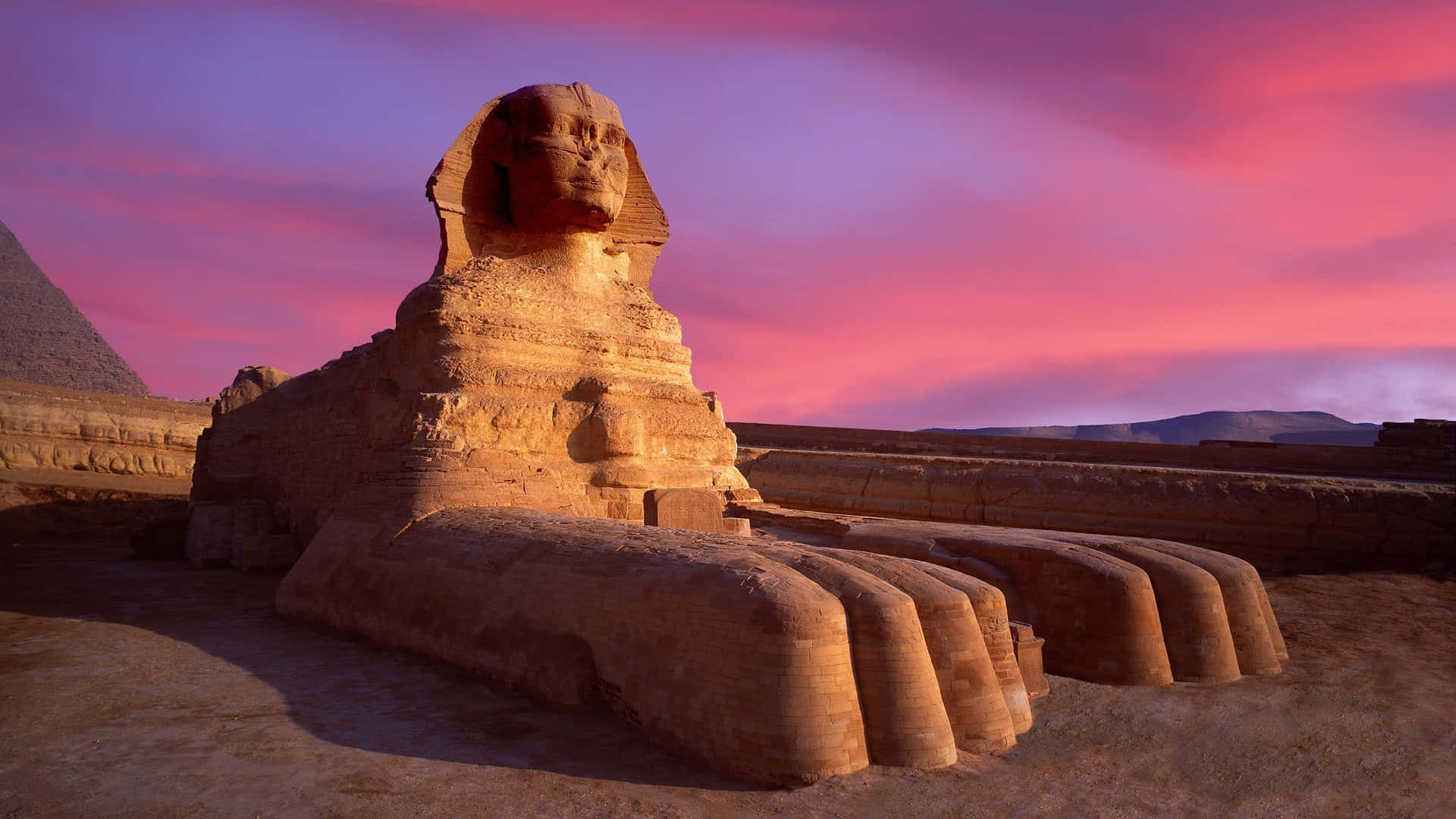 A Sphinx And Pyramids At Sunset Background