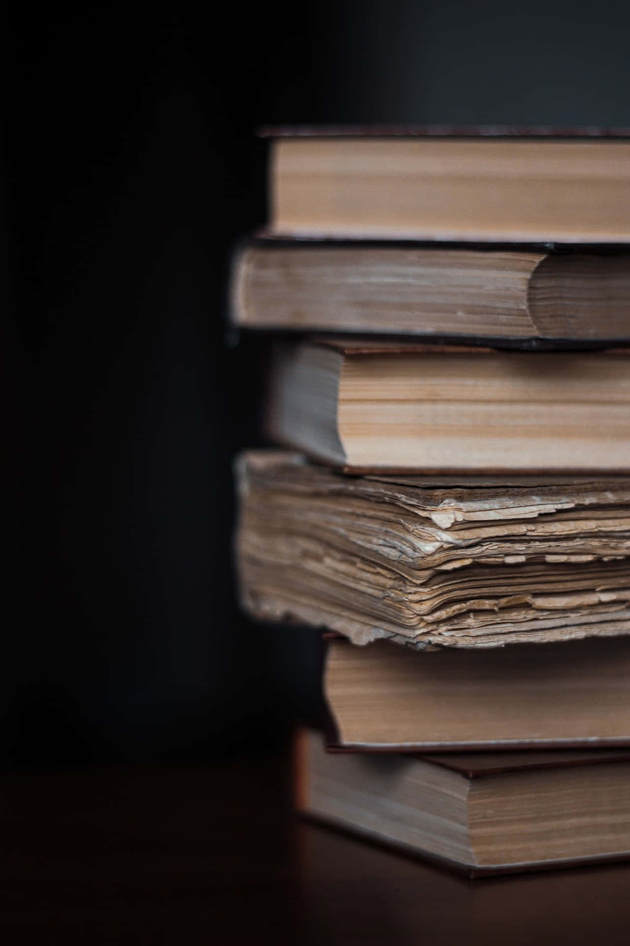 A Stack Of Books On A Table With A Dark Background Background