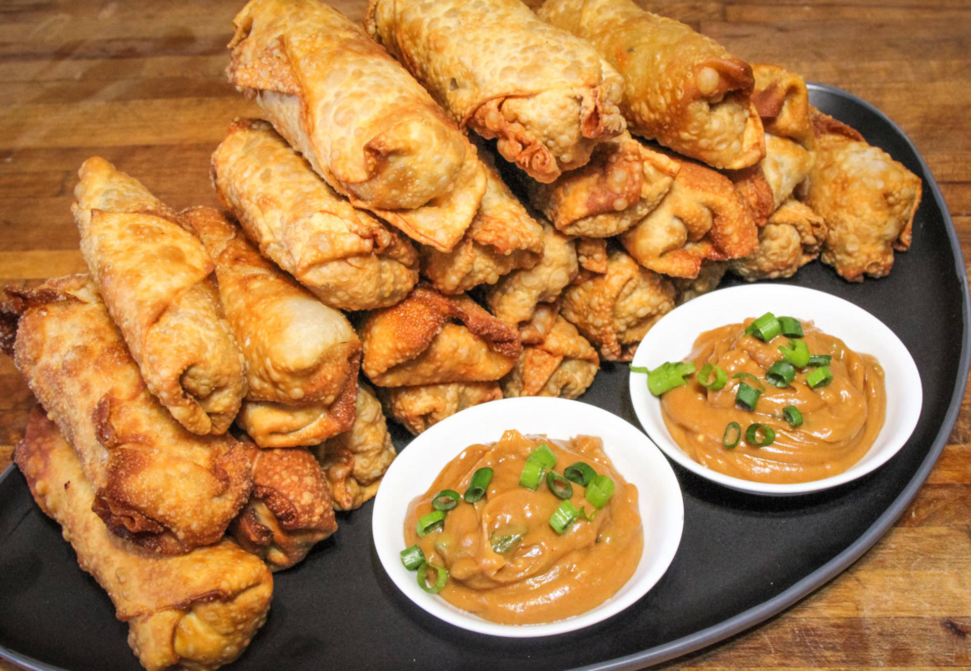 A Stack Of Delectable Egg Rolls With Savory Peanut Sauce
