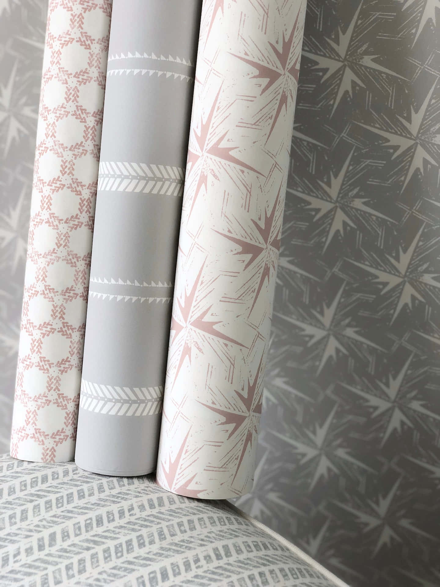 A Stack Of Pink And Grey Wallpapers On A Bed Background