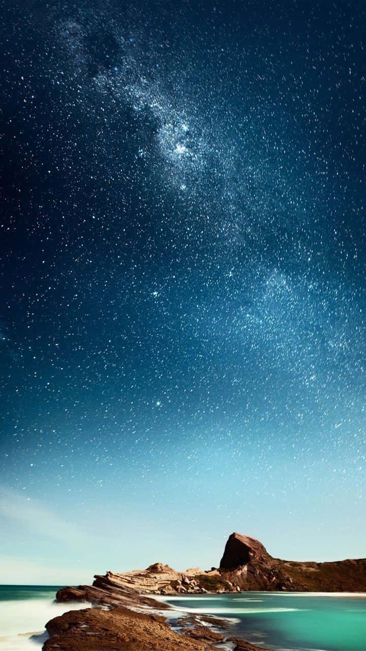 A Starry Sky Over A Rocky Beach