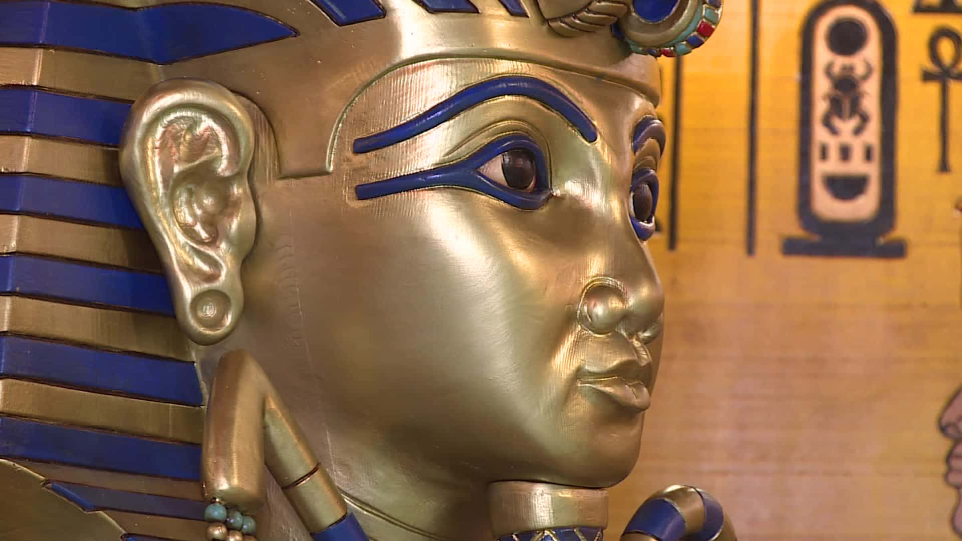 A Statue Of An Egyptian Pharaoh With Gold And Blue Eyes Background