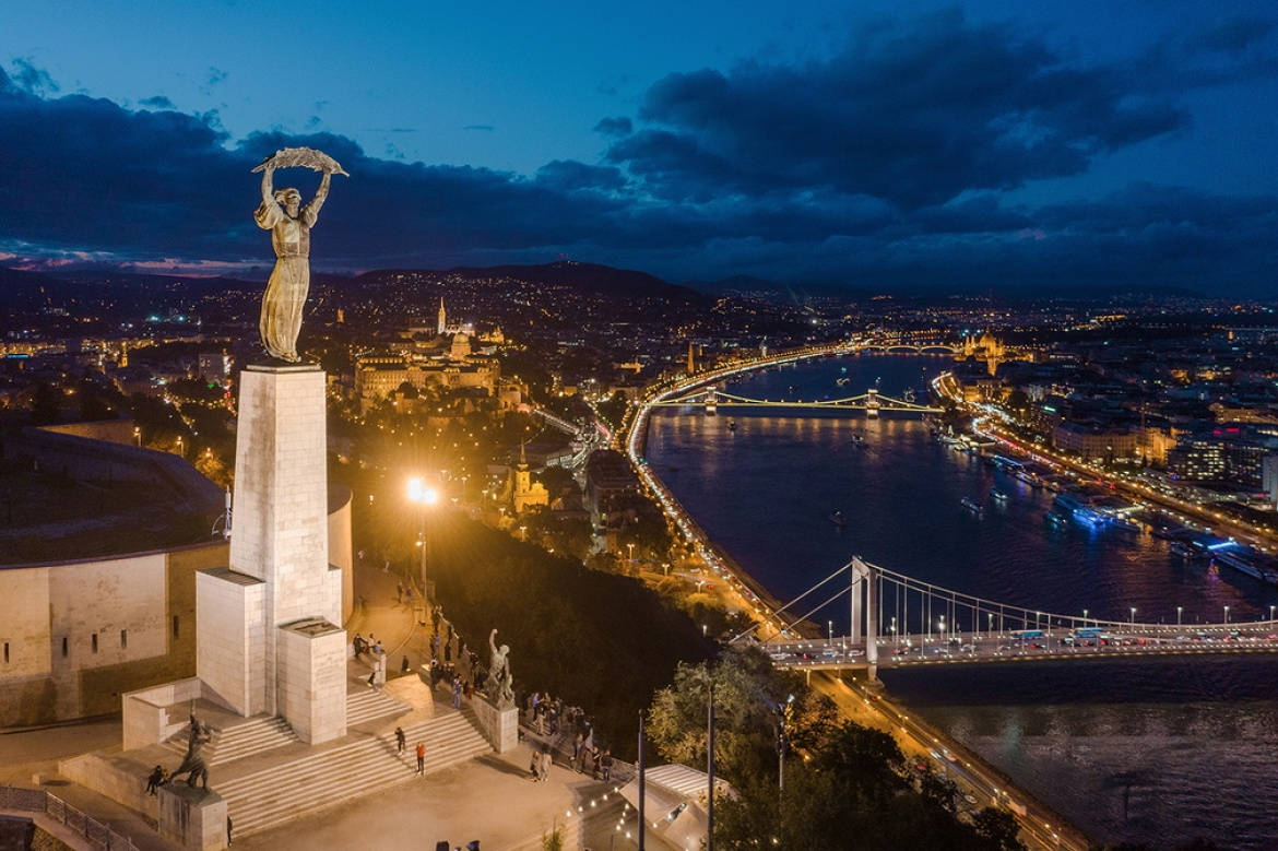 A Statue Of Liberty Overlooking The River And City At Night