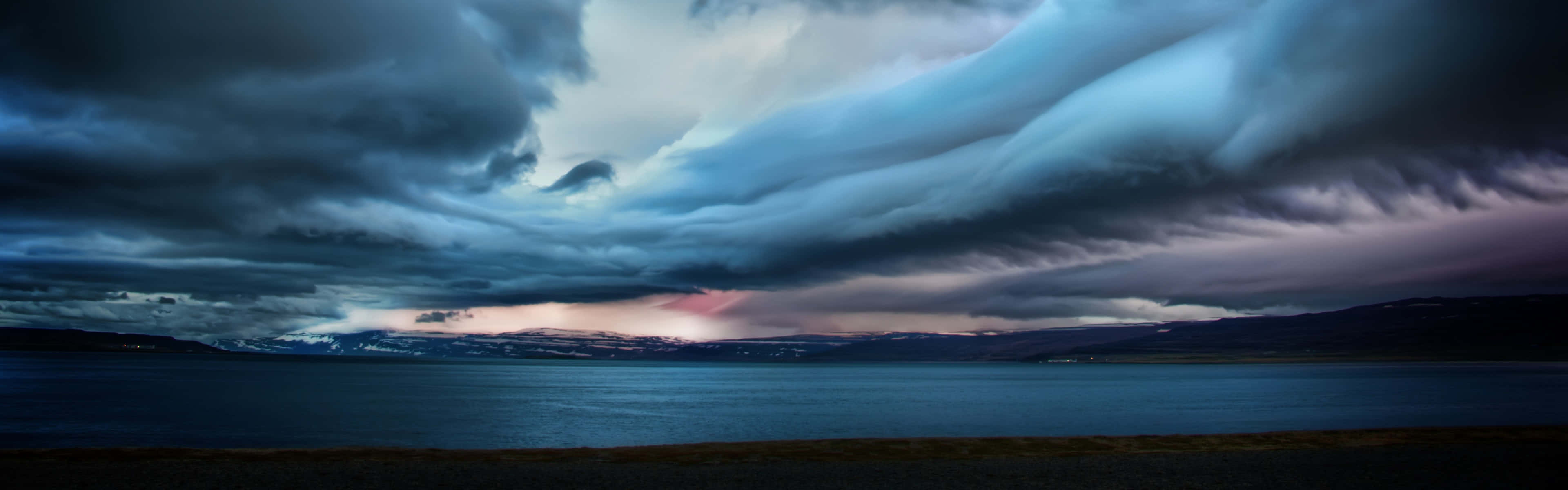 A Stormy Sky Over A Lake And Mountains Background