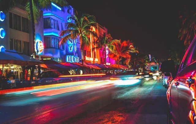 A Street Scene With Neon Lights And Palm Trees Background