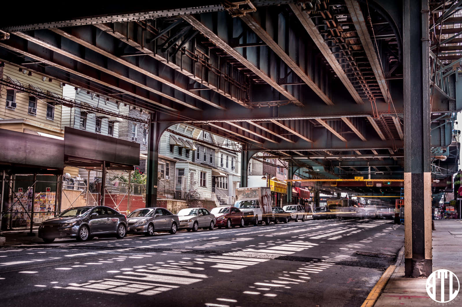 A Street With Cars Parked Under A Bridge Background