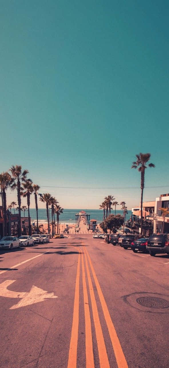 A Street With Palm Trees And A Beach