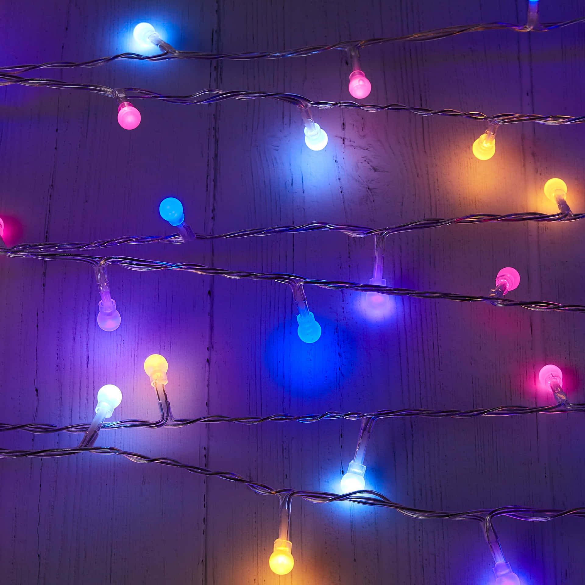 A String Of Multi Colored Lights On A Wooden Surface Background