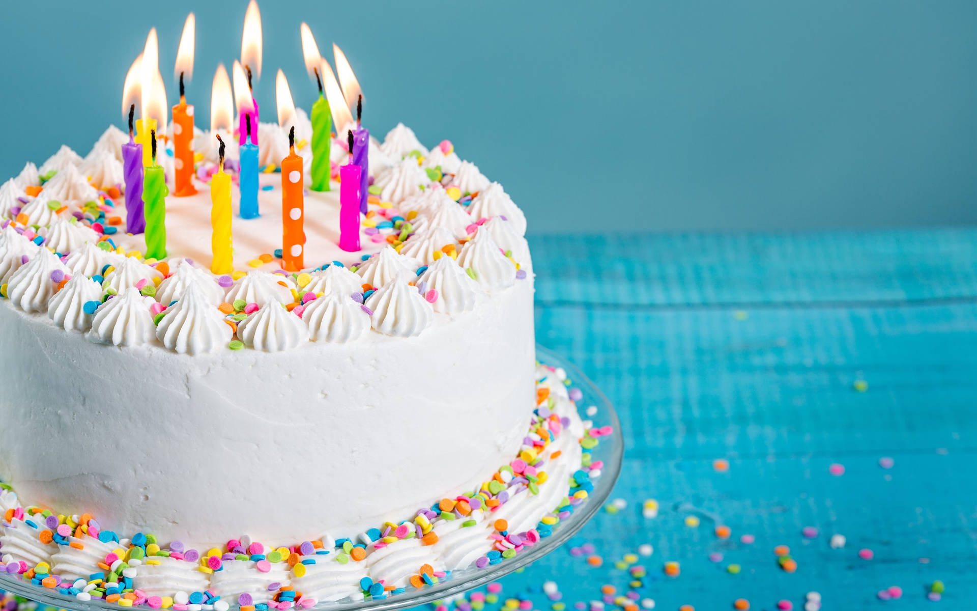 A Stunning White Birthday Cake Adorned With Lit Candles Background