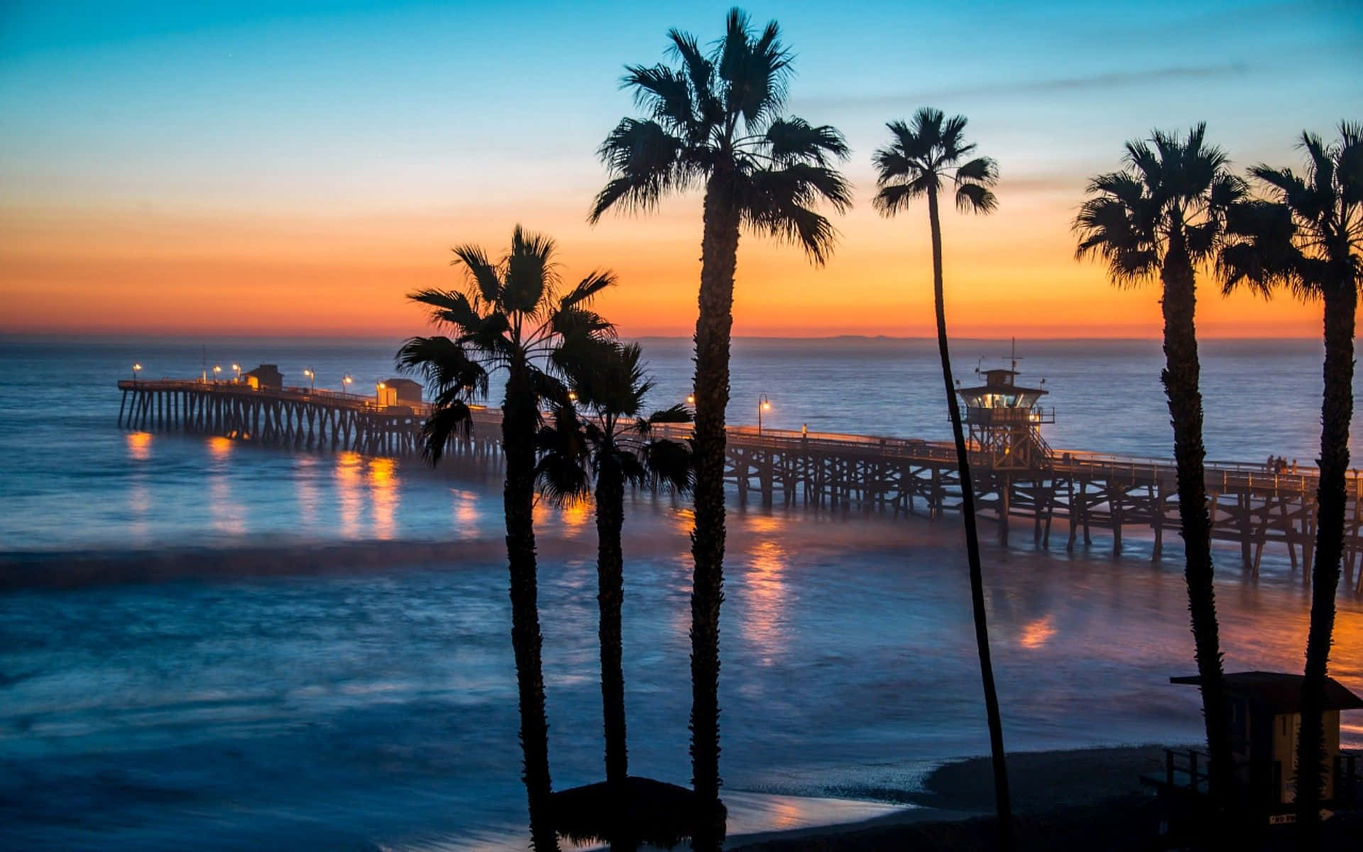 A Sunrise Glows Atop The Malibu Beach Shoreline Background