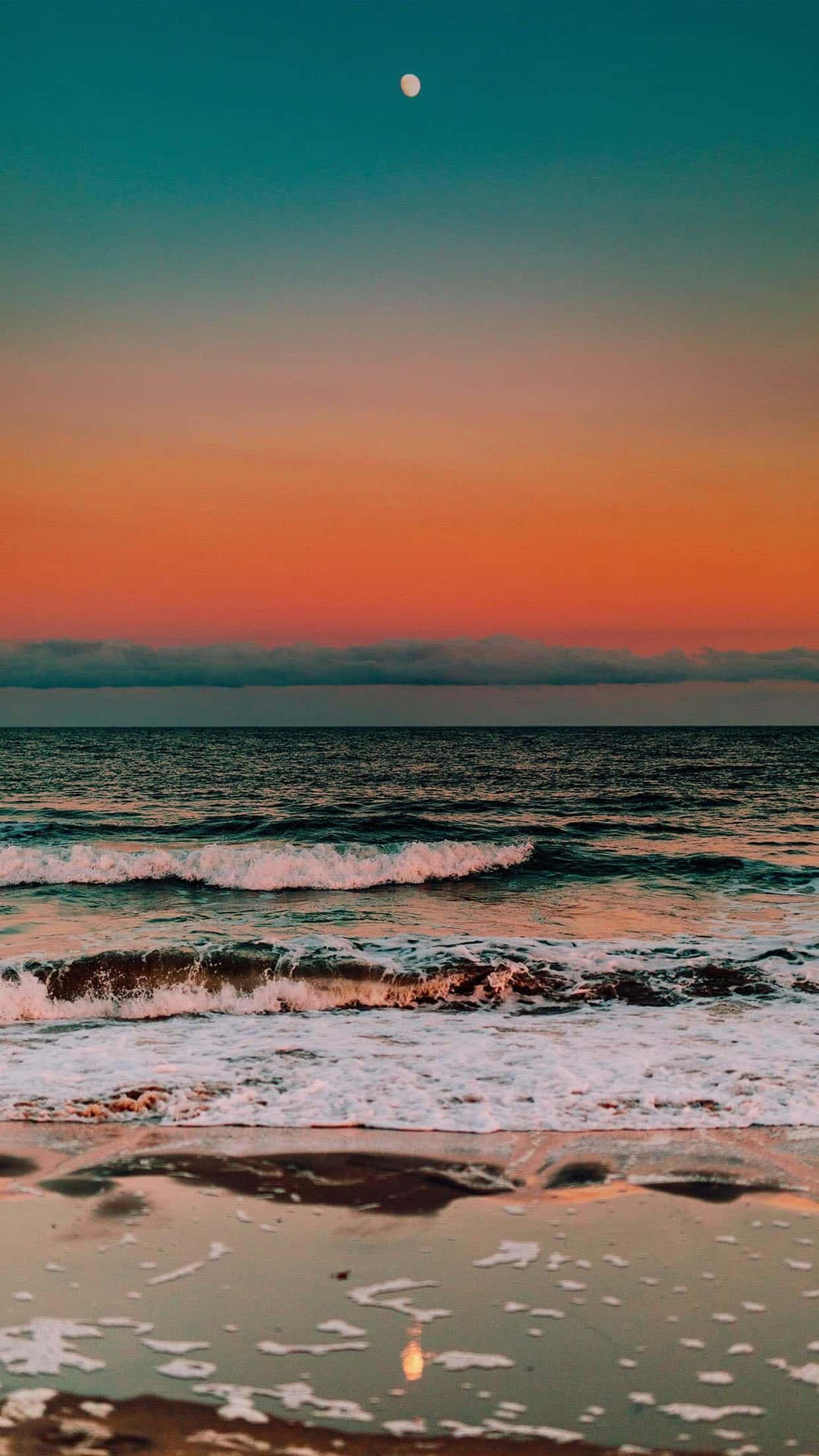 A Sunset On The Beach With The Moon Reflecting In The Water