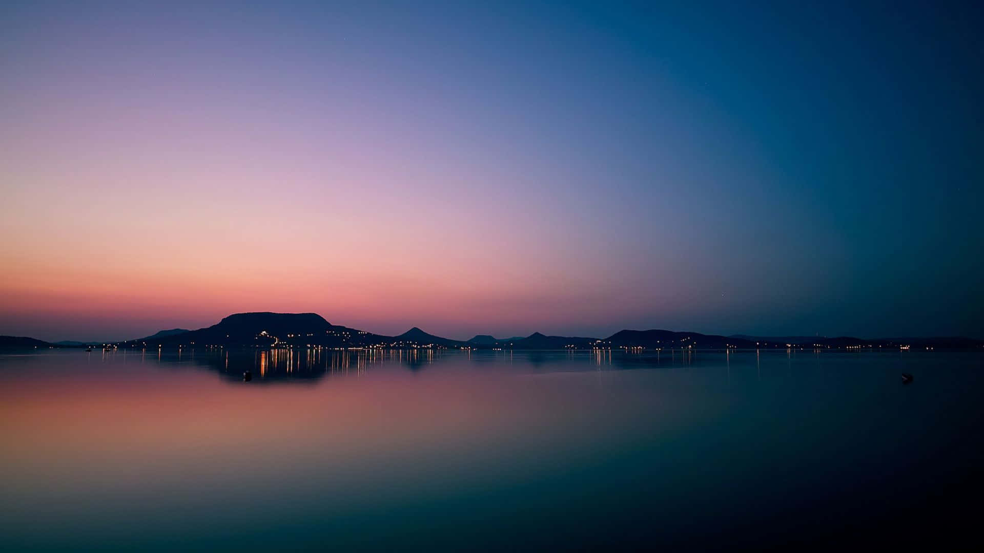 A Sunset Over A Lake With Mountains In The Background Background