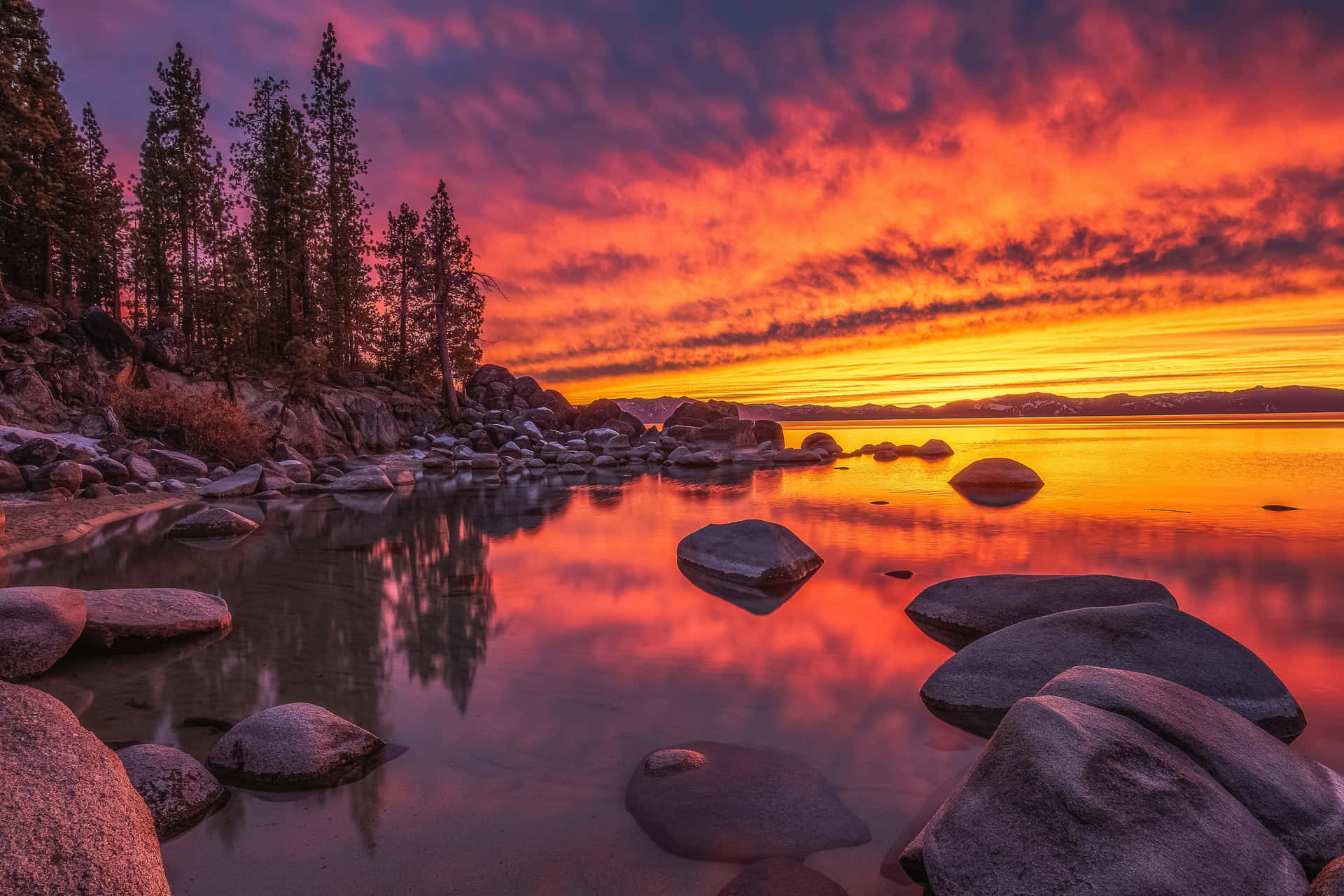 A Sunset Over A Lake With Rocks And Trees Background