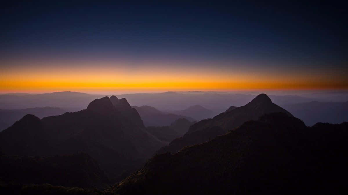 A Sunset Over Mountains With Mountains In The Background Background