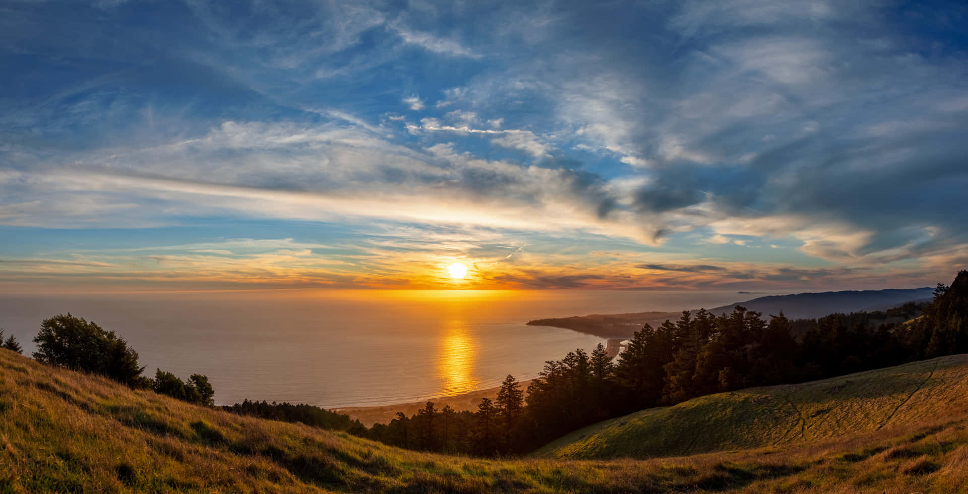 A Sunset Over The Ocean From A Hillside Background