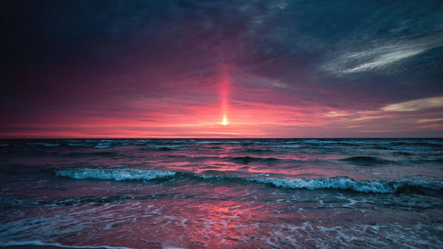 A Sunset Over The Ocean With A Red Light Shining Background