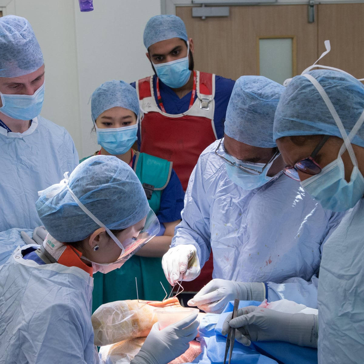 A Surgeon Performing Surgery In Operating Theatre Background