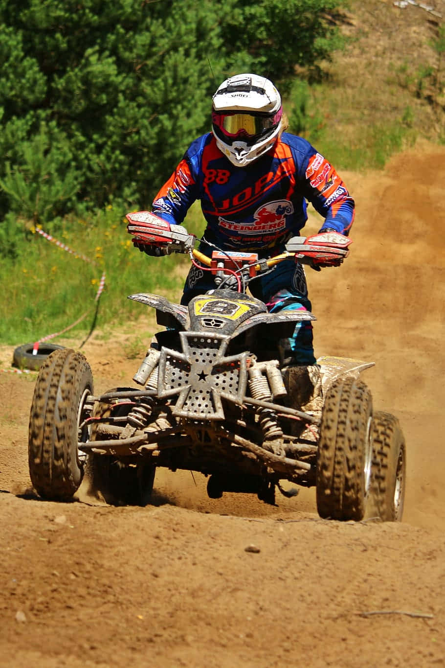 A T V Racerin Actionon Dirt Track Background