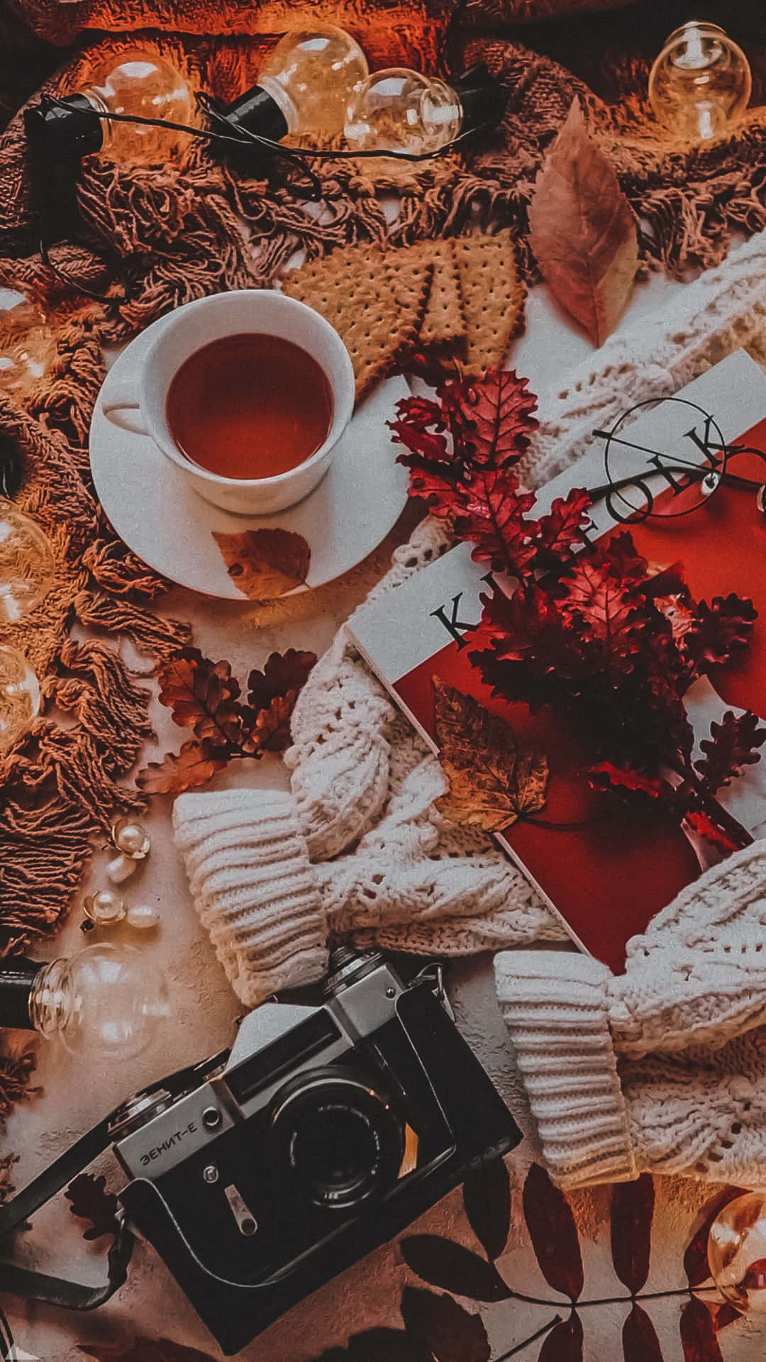 A Table With A Cup Of Tea, A Camera And Leaves