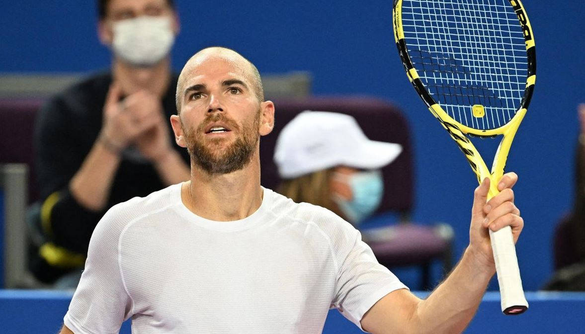 A Tennis Player Holding Up His Racket On A Court Background