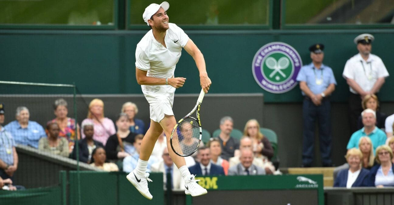 A Tennis Player In The Air While A Crowd Watches