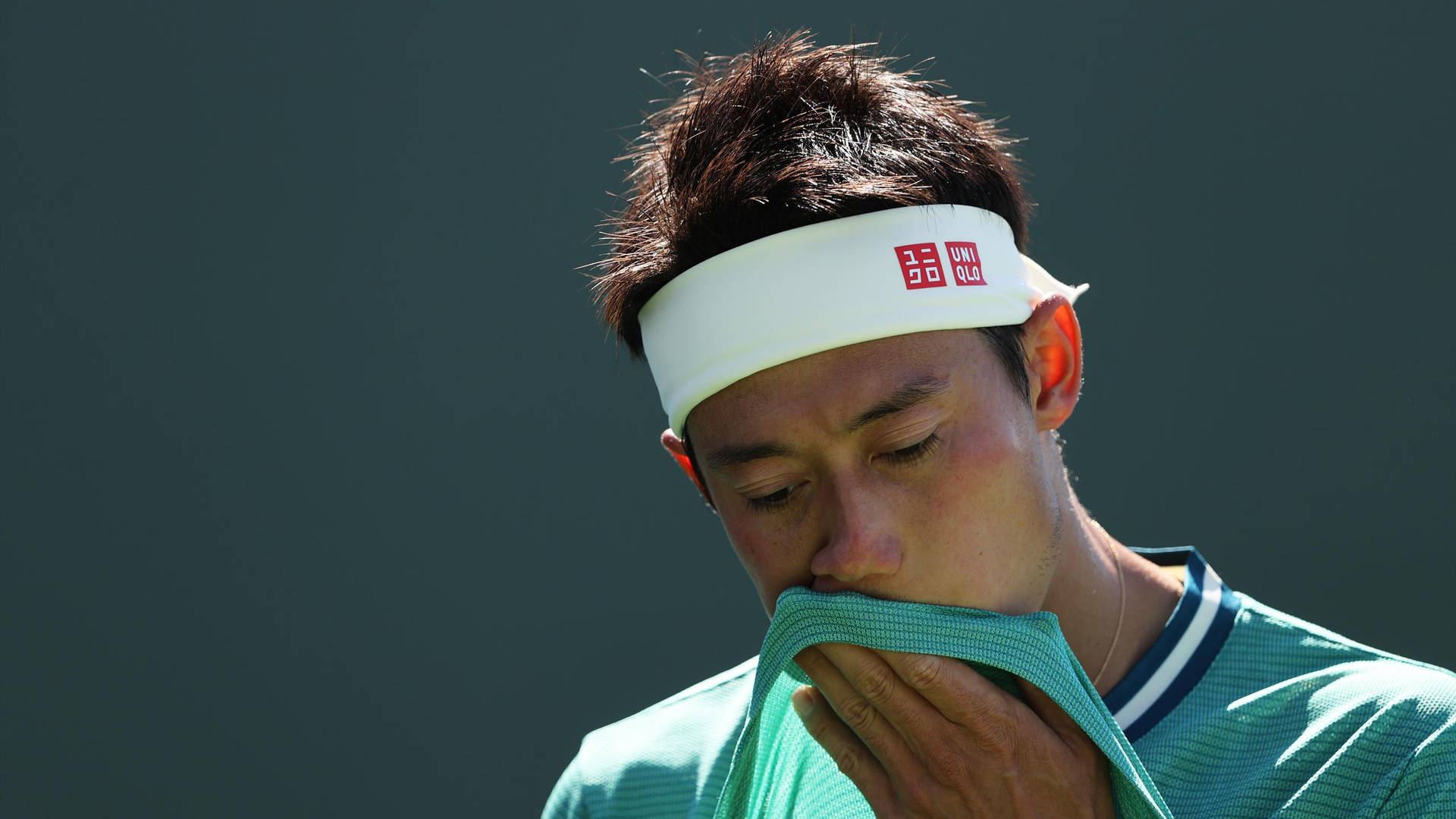 A Tennis Player Is Wiping His Face With A Towel Background