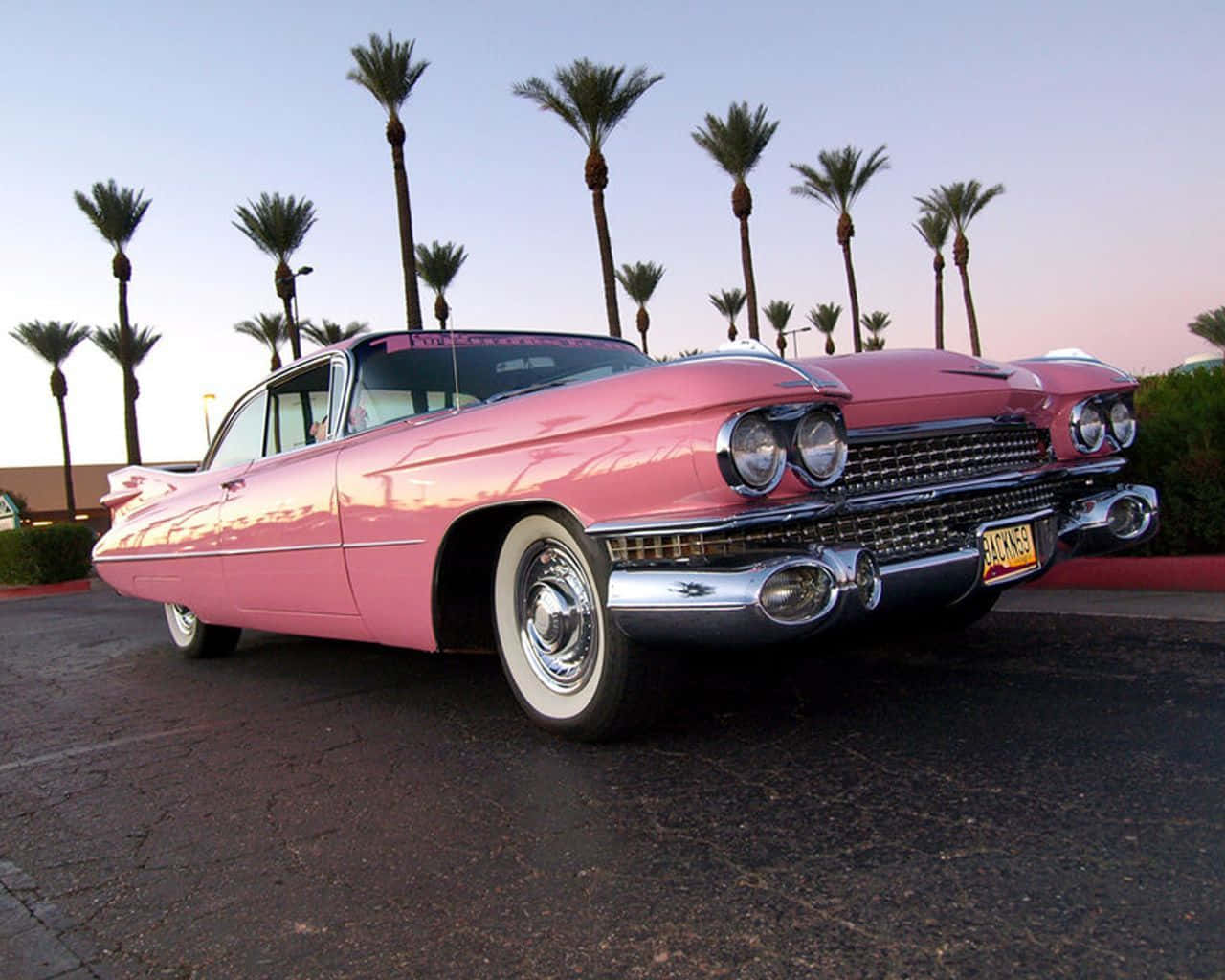 A Timelessly Elegant Pink Vintage Car Stands In The Setting Sun Background