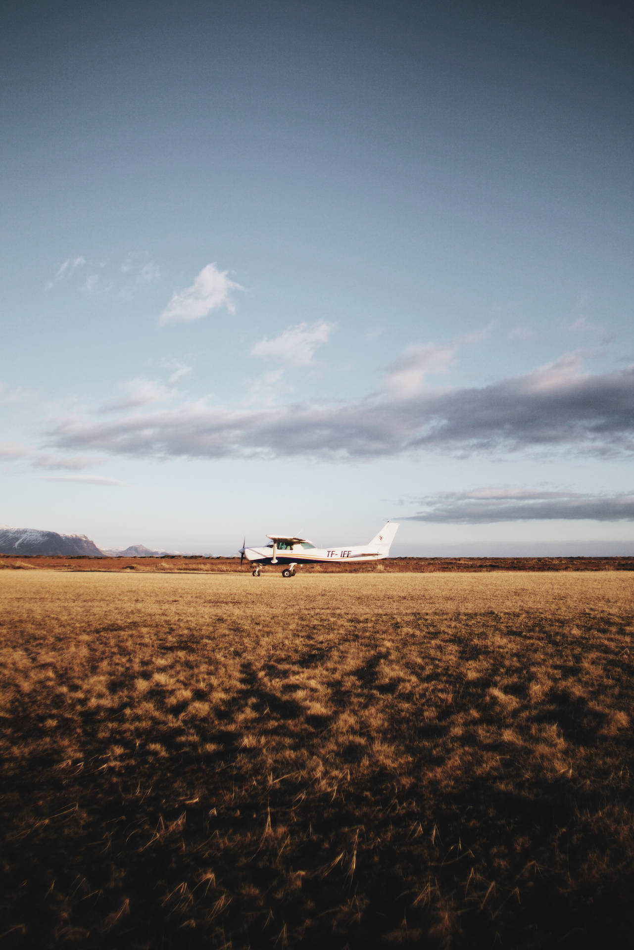 A Tinny White Plane Waiting For Takeoff In Open Field Background