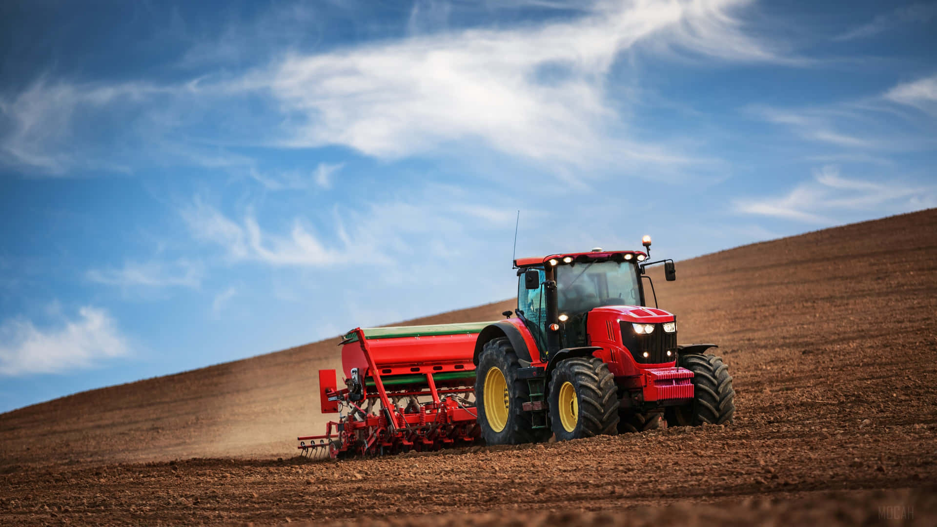 A Tractor Plowing A Field With A Blue Sky Background