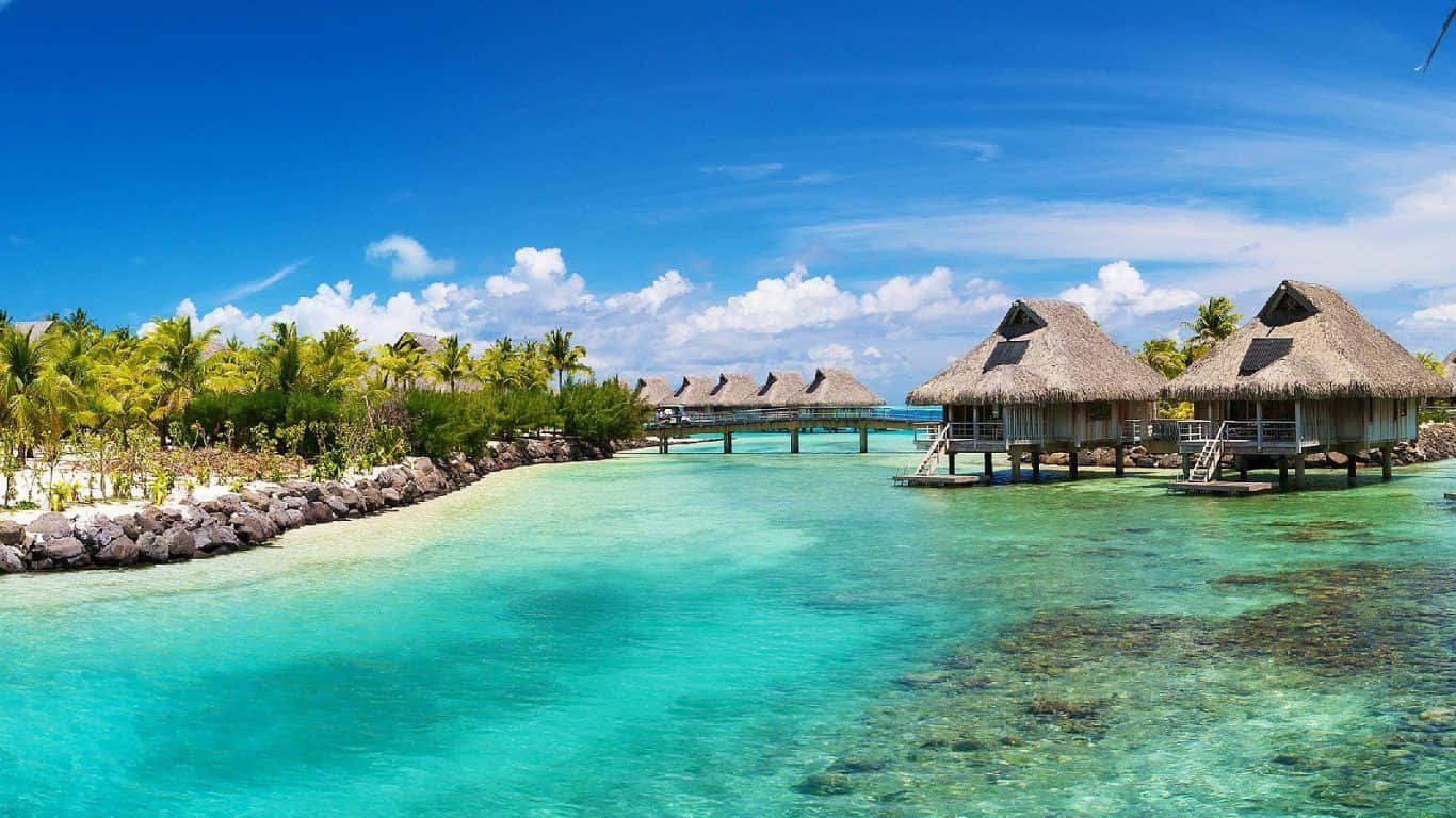 A Tropical Island With Thatched Huts And Clear Water Background