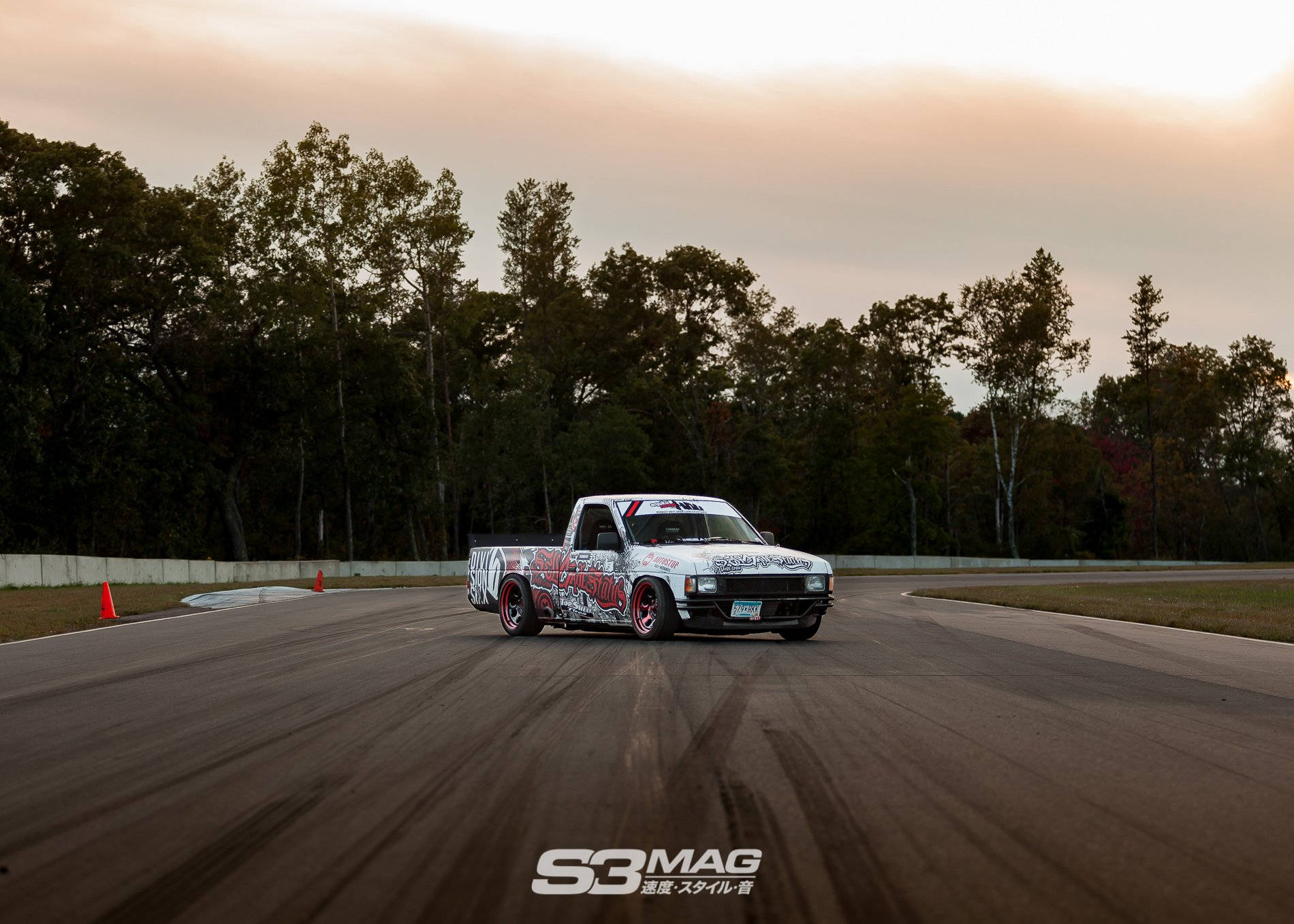 A Truck Driving Down A Track In The Evening Background