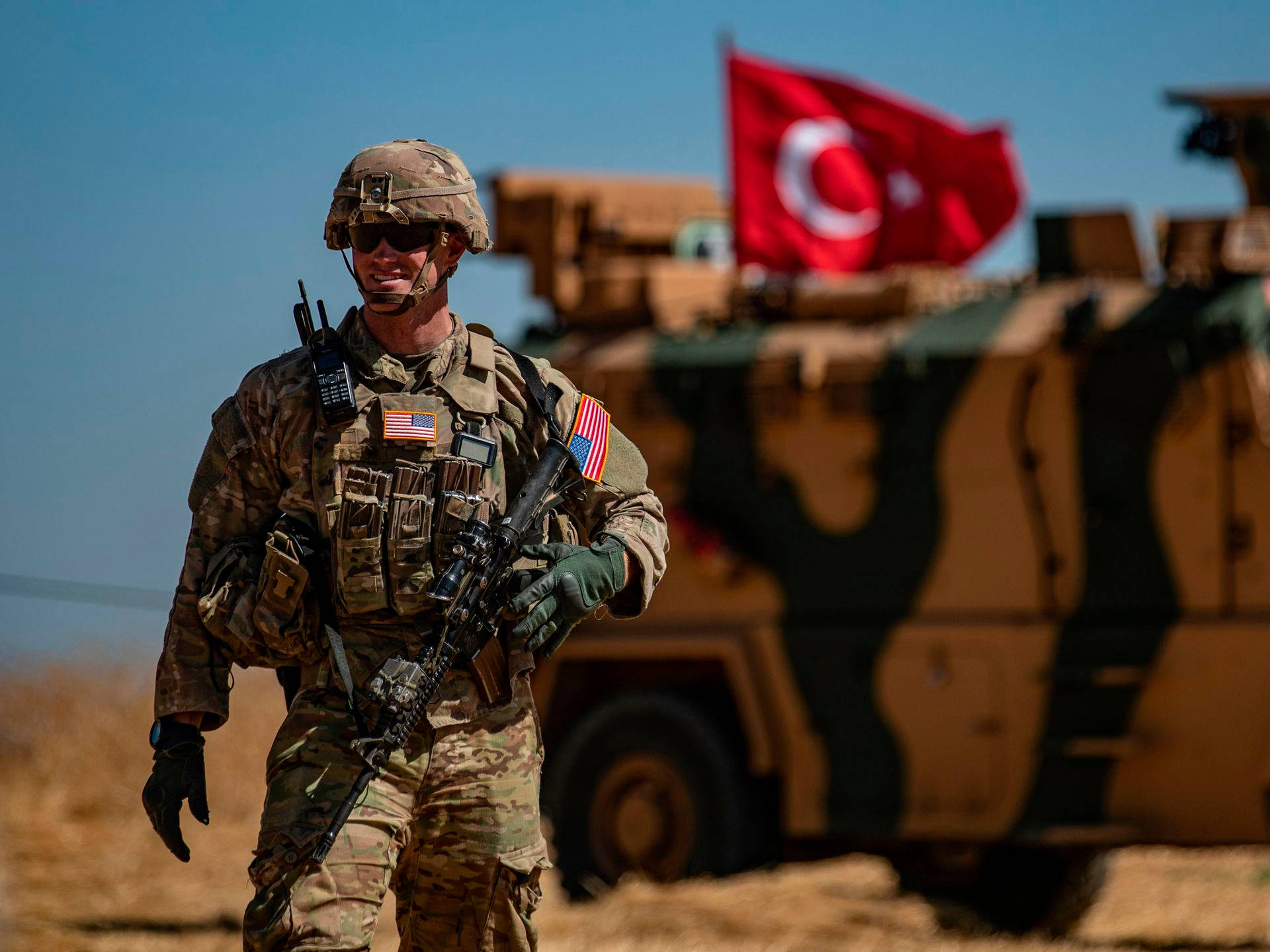 A Turkey Soldier Standing Tall With The American Flag.